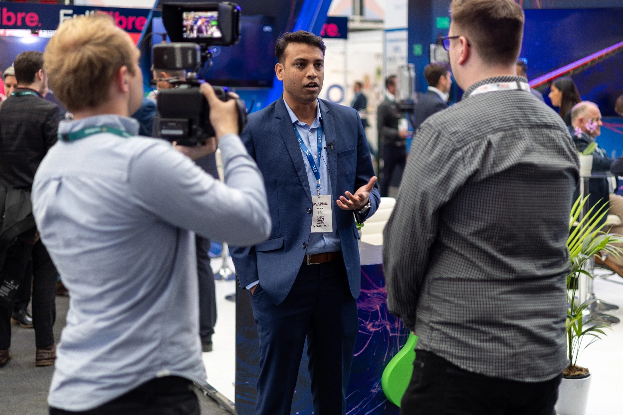 An event videographer from Medialook filming an interview at an STL trade show booth